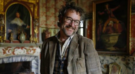 Imagen de un hombre con cuadros históricos en el fondo